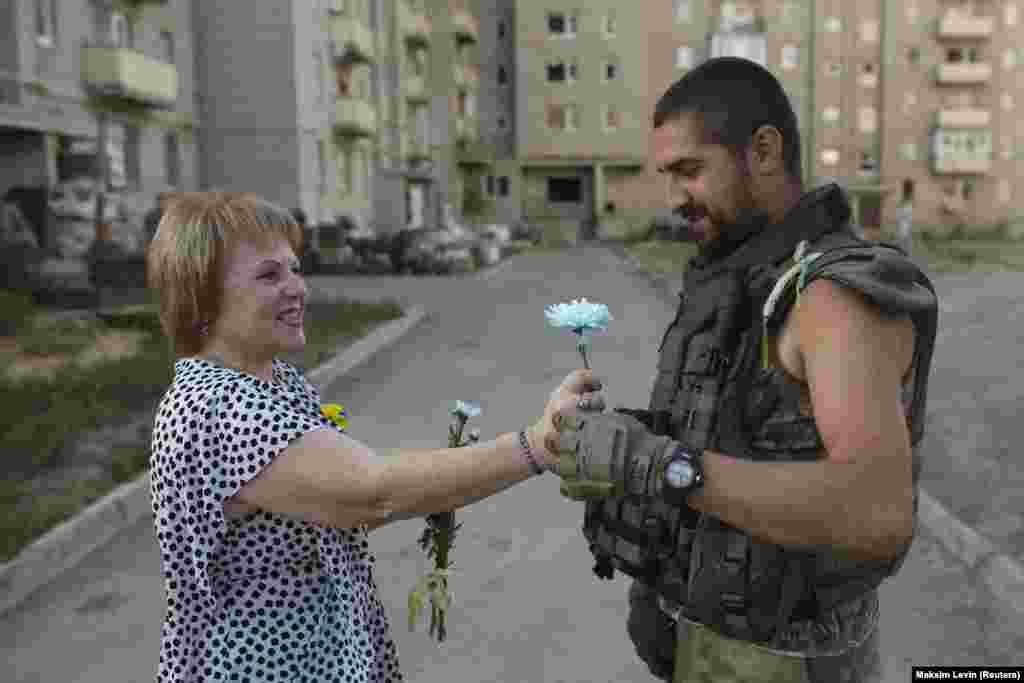 Женщина дарит цветок украинскому военнослужащему во время празднования Дня Независимости в Авдеевке, Донецкой области, 24 августа 2015 года