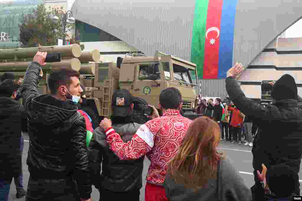 Зрители машут руками и снимают видео, когда мимо проезжает система залпового огня Т-300 &laquo;Касирга&raquo; турецкого производства