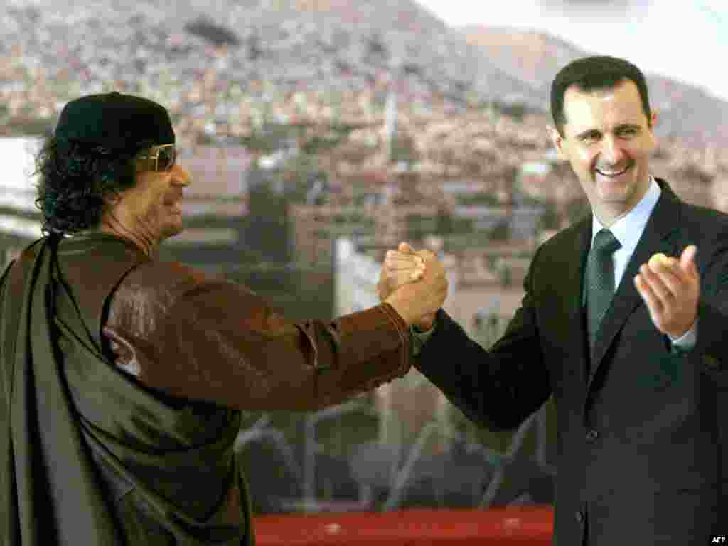 Syrian President Bashar al-Assad, who has dealt with his own antigovernment protests with a violent crackdown, clasps hands with Qaddafi at the opening session of the Arab Summit in Damascus on March 29, 2008.