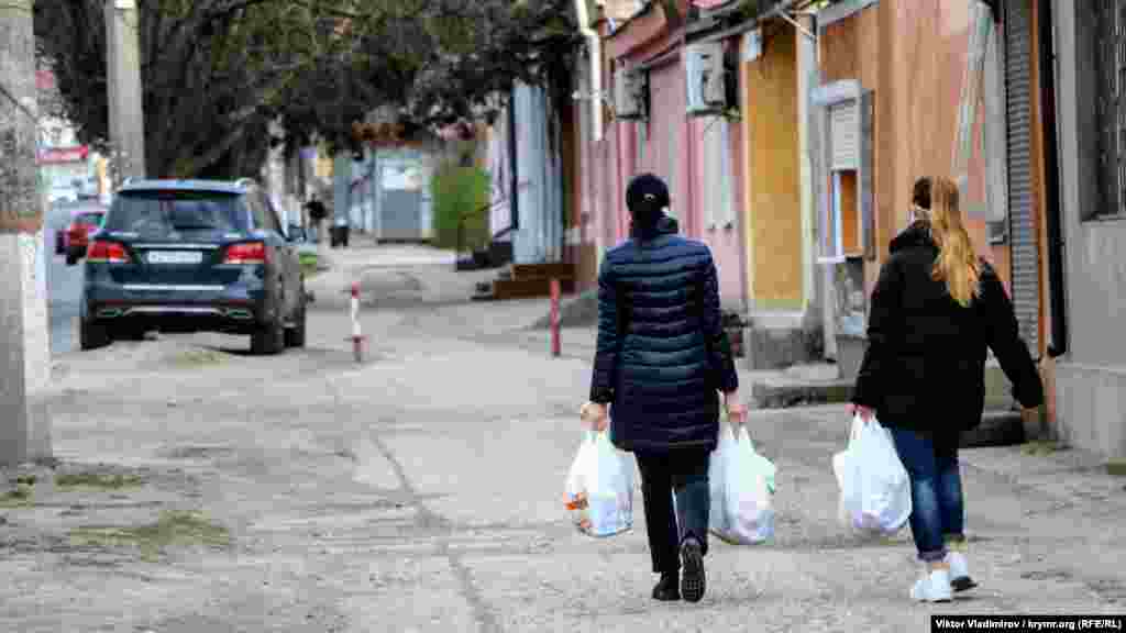 Редкие прохожие возвращаются из магазина домой