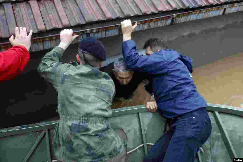 Обреновац қаласы тұрғынын суда қалған үйінен шығарып алуға көмекке келген сербиялық сарбаздар.